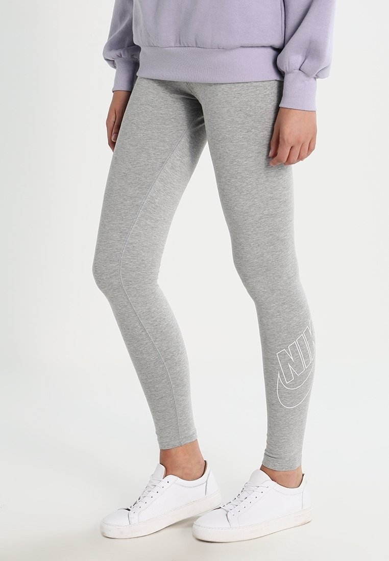 Grå leggings i mjukt material med slim fit, med en vit Nike-logotyp på underbenet, tillsammans med vita sneakers.