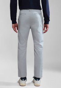Chinos de color gris claro, fabricados en algodón, con corte recto, bolsillos traseros y combinados con zapatillas deportivas en azul marino y blanco.