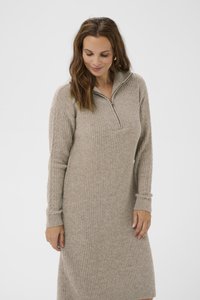 Robe tricot beige avec un col zippé mi-hauteur, texture côtelée et manches longues. Présente des poignets ajustés et une silhouette décontractée.