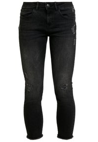 Jeans skinny de mezclilla negra con detalles desgastados, cinco bolsillos y dobladillo desflecado. El material presenta un ligero brillo y suavidad.