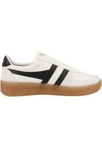 Sneaker bianco in pelle con strisce nere, punta arrotondata e suola in gomma. Presenta lacci e una superficie liscia. Vista laterale illuminata.
