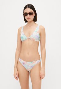 Bikini i to deler med et pastellfarget blomstermønster i nyanser av grønt, oransje og lilla. Mykt stoff, trekantet topp og lavt liv.