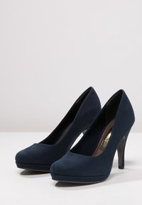 Zapatos de tacón alto de ante azul marino con puntera redondeada, silueta elegante y tacón de aguja, presentando una textura suave y sin adornos visibles.