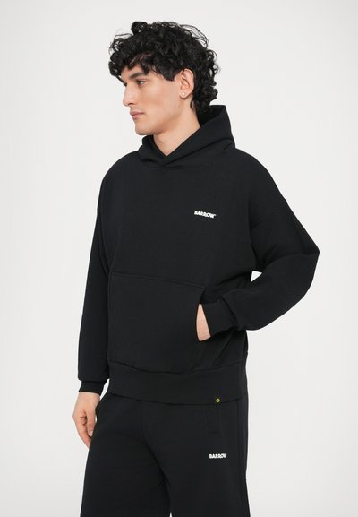 Hanorac negru cu glugă, realizat din bumbac, având un buzunar frontal și un mic logo alb pe piept. Croială lejeră cu manșete ribb.