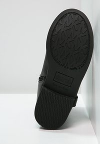 Černá syntetická bota s texturovanou gumovou podrážkou. Obsahuje boční zip a na podrážce nese branding "Michael Kors". Podrážka nešpiní.