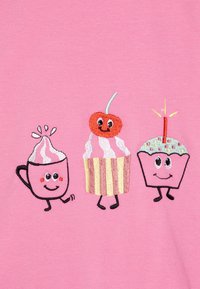 Design ricamato che presenta una tazza rosa con panna montata, un cupcake con una ciliegia sopra e un cupcake con una candela, il tutto su uno sfondo rosa.