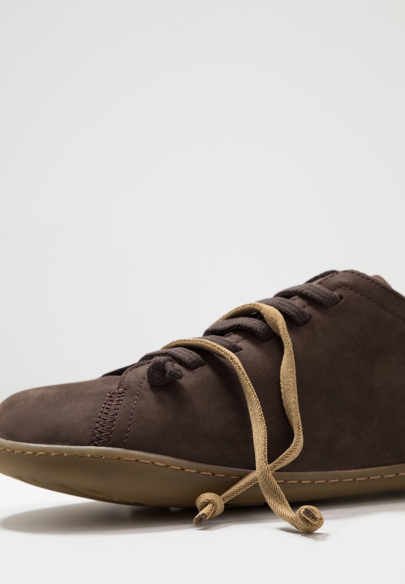 Bruine leren schoen van suede met een ronde neus, vastgebonden met een lichtbruine veters. Kenmerkt zichtbare stiksels en een flexibele rubberen zool.