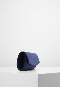 Pochette bleu marine avec une texture douce, de forme arrondie et une fermeture à rabat. Design minimaliste, adaptée à diverses occasions.