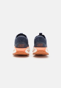 Mørkeblå Nike løbesko med struktureret stof, orange accenter og en hvid mellemsål. Har en pull tab ved hælen for nem påtagning.
