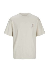 Camiseta de algodón beige con mangas cortas y cuello redondo. Presenta un pequeño gráfico floral en azul y púrpura en el área del lado izquierdo del pecho.
