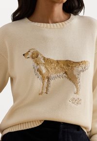 Cream sweater featuring a detailed, knitted golden retriever design. Ribbed neckline and hem, with embroidered initials at the bottom.