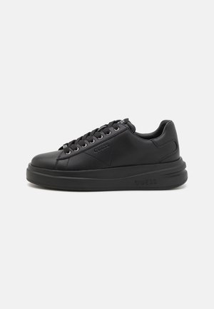 Sort lavtop sneaker med tyk sål, snørebånd foran og præget Guess-logo på siden og sålen.