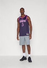 Košarkaška dres u tamnoplavoj boji s ljubičastim detaljima i natpisom "Vukovi", u kombinaciji s svijetlosivim šortsevima i crnim tenisicama.