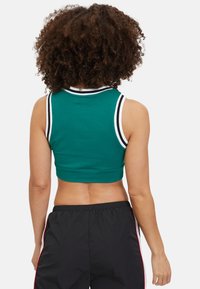 Top corto verde hecho de una tela suave, con un escote acanalado que presenta rayas blancas y negras. El diseño de la parte posterior es simple y ajustado.