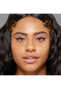 Tortoiseshell hair clips with a glossy finish, securing wavy dark hair. Soft pink makeup accents the eyes, with a natural lip color.