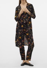 Blommig svart kimono-jacka över matchande byxor, med livfulla gula och rosa blommor, lättviktsmaterial och lös passform. Platta svarta skor.