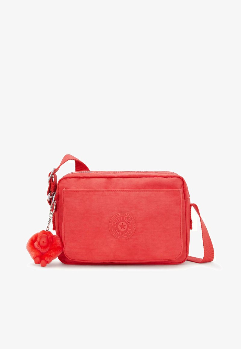 Czerwona torba crossbody Kipling o teksturowanej powierzchni, prostokątnym kształcie, z zamkiem błyskawicznym oraz odczepianą zawieszką w kształcie goryla z pomponem.