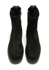 Une paire de bottines noires en daim avec des bouts carrés, des fermetures éclair latérales et des tirettes avec des détails métalliques, sur fond blanc.