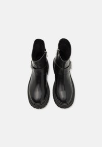 Botine negre până la gleznă, fabricate din piele lucioasă, cu vârf rotunjit, fermoare laterale și talpă din cauciuc texturat. Include accente din metal argintiu.