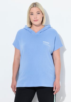 Felpa corta azzurra con maniche corte e collo a V, con dettagli testuali sul davanti. Tessuto morbido con una vestibilità comoda, abbinata a pantaloni neri con dettagli laterali.
