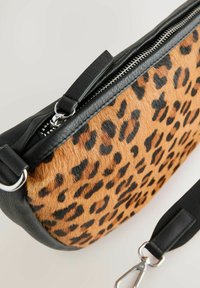 Tasche im Leopardenmuster mit einer strukturierten Vorderseite aus braunem und schwarzem fellartigem Material, glatten schwarzen Lederseiten und einem silbernen Reißverschluss.