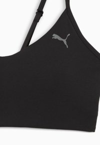Melnā sporta krūšturis ar gludu tekstūru, kuram ir regulējamas siksniņas un gaiši pelēks Puma logo kreisajā pusē.