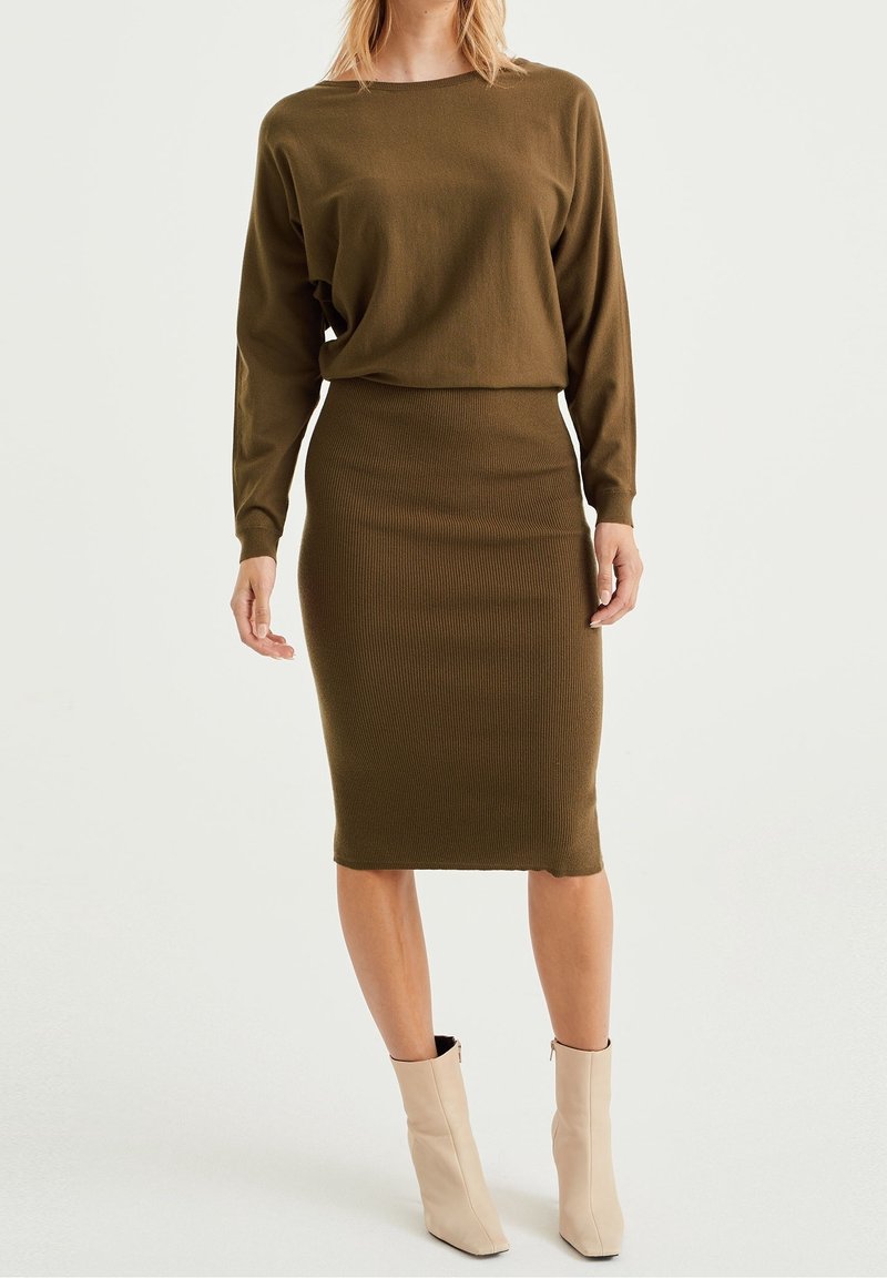 Top en tricot vert olive à manches longues associé à une jupe midi côtelée ajustée. La tenue présente un design simple et une texture lisse.