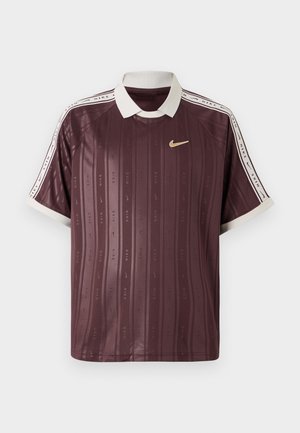 Bordový polo tričko Nike s bielym golierom a akcentmi na rukávoch. Obsahuje vertikálne pruhy a opakované logo. Ľahký, hladký materiál.