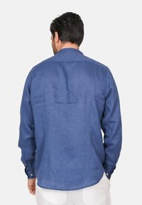 Camicia blu a maniche lunghe realizzata in tessuto leggero. Presenta un colletto classico e polsini con bottone, con una texture liscia e una vestibilità casual.