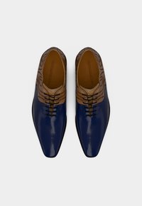 Μπλε παπούτσια από δέρμα πατέντας με καφέ υφασμάτινο άνω μέρος που διαθέτει κυματιστό σχέδιο, μυτερή μύτη και μαύρα κορδόνια σε λείο πάτο.