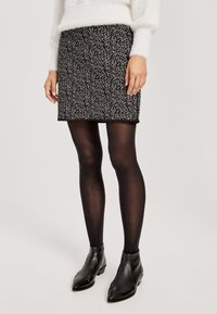 Czarna spódnica w białe plamki, dopasowany krój, długość do połowy uda. Noszona z czarnymi, nieprzezroczystymi rajstopami i czarnymi, szpiczastymi botkami za kostkę. Biały, puszysty sweter.