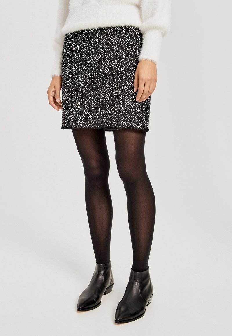Czarna spódnica w białe plamki, dopasowany krój, długość do połowy uda. Noszona z czarnymi, nieprzezroczystymi rajstopami i czarnymi, szpiczastymi botkami za kostkę. Biały, puszysty sweter.