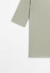 Haut en maille côtelée vert clair à manches courtes avec un col rond, présenté partiellement sur un fond blanc uni.