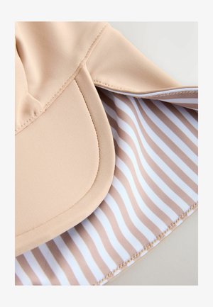 Beežikaarelise nokaga pehme kangast nokamüts. Sisevooder, millel beeži ja valge triibuline muster. Õmbluse detailid nähtavad.