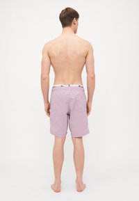 Shorts de baie pentru bărbați, în roz deschis, realizate dintr-un material ușor. Dispune de un brâu elastic cu branding și un singur buzunar pe spate.