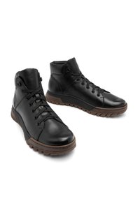 Czarne skórzane buty za kostkę z teksturowanym wykończeniem, z zawiązywaniem i gumową podeszwą z brązowym wzorem bieżnika.