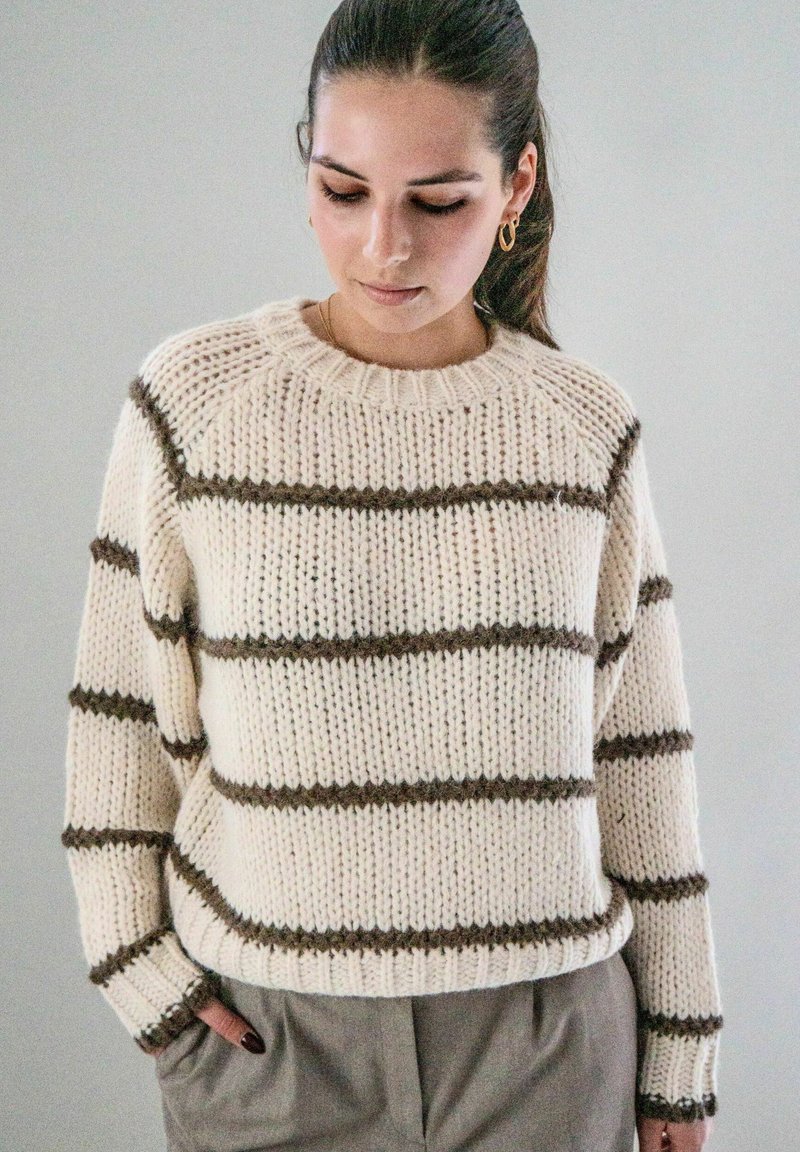 Crème gebreide trui met bruine horizontale strepen en geribde manchetten, met een ronde halslijn en een losse pasvorm. Zachte textuur, casual ontwerp.