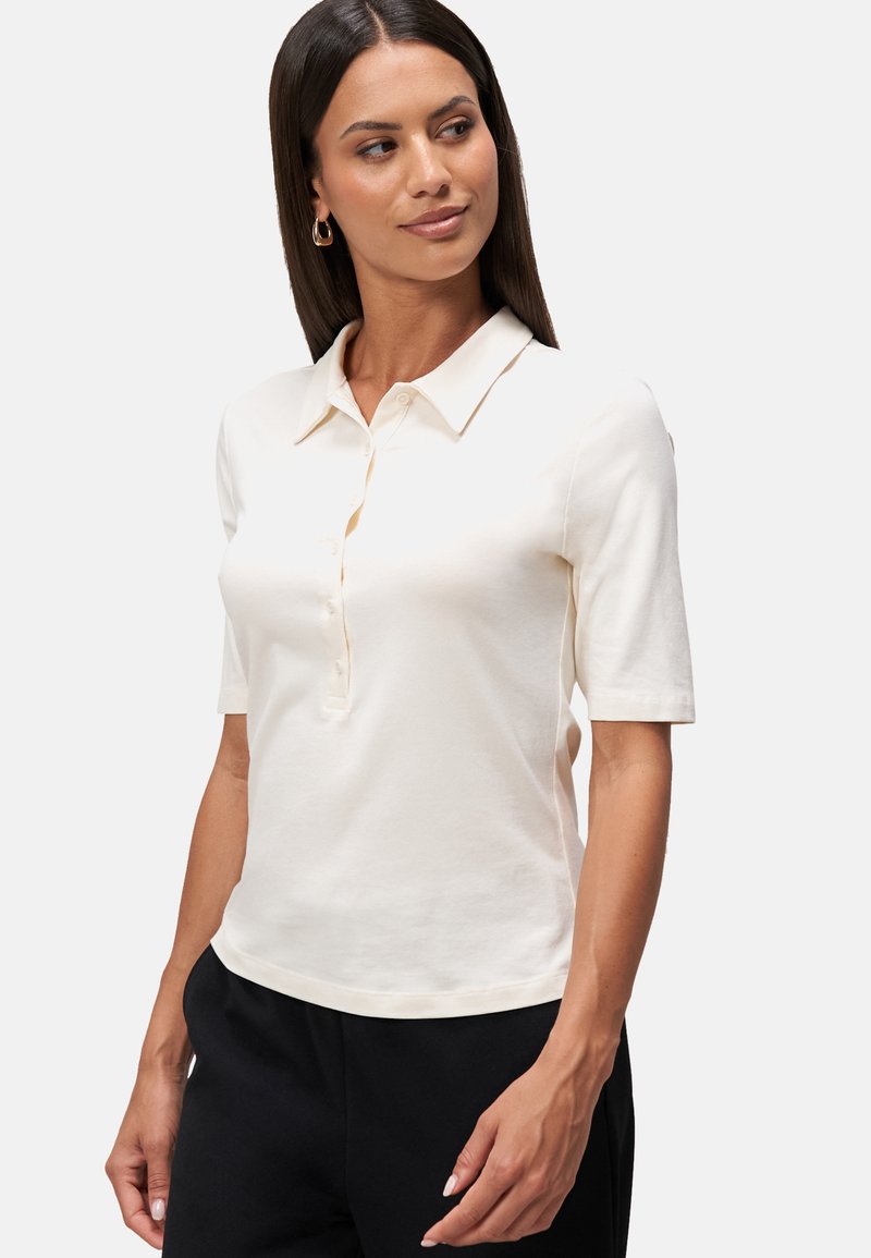 Polo shirt à manches courtes en coton écru, dotée d'un col, d'une patte de boutonnage et d'une coupe ajustée. Texture lisse, style simple.