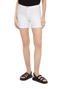 Witte denim shorts met een opgerolde zoom, voorzien van een knoopsluiting en voorzakken, gecombineerd met zwarte sandaaltjes met bandjes.