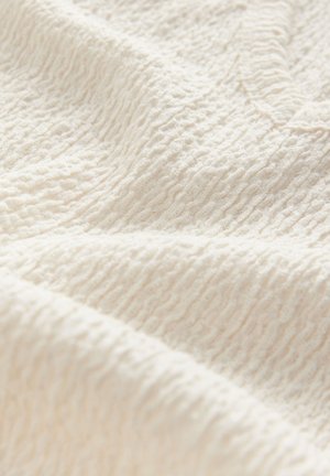Tejido texturizado de color blanco roto con un patrón arrugado, que muestra una superficie suave y ligeramente elevada adecuada para prendas de vestir o textiles para el hogar.
