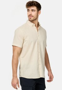 Korte mouw, lichtbeige knoopshirt met een linnen-achtige textuur, voorzien van een klassieke kraag en subtiele stikseldetails.