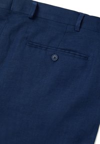 Pantaloni in lino blu navy con una tasca posteriore singola con chiusura a bottone e una texture liscia, che mostra un sottile motivo in tessuto.