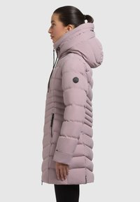 Chaqueta larga acolchada en rosa claro, con un cuello alto, capucha con cordón, cremalleras laterales y un diseño de acolchado texturizado.