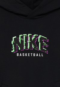Čierna mikina s kapucňou s výrazným vyšívaným logom "NIKE" v zelenej a fialovej farbe s efektom poruchy, a "BASKETBALL" v bielej farbe nižšie.