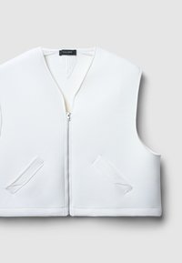 Gilet bianco senza maniche con scollo a V, zip frontale e due tasche angolate. Realizzato in tessuto liscio con dettagli di cucitura visibili.