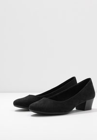 Chaussures basses en suède noir à talon bas, avec un bout arrondi et une texture lisse. Dotées d'un talon carré modeste pour plus de stabilité.