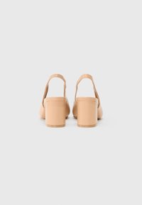 Nude, slingback hakjes met een soepele leren afwerking en een blokhak. Het ontwerp heeft een ronde neus en minimale hardware.