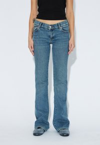 Ljusblå utsvängda jeans med knappstängning, framfickor och en blekt textur, som sitter vid midjan. Slätt tyg med lätt stretch.