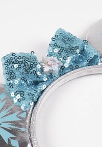 Fascia argentata con un grande fiocco blu di paillettes e un emblema di personaggio, decorata con motivi di fiocchi di neve blu chiaro.