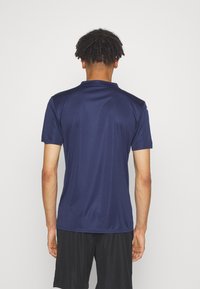 Marinblå, kortärmad sporttröja med ett slätt, lätt tyg; har en krage och en subtil logotyp på axeln.